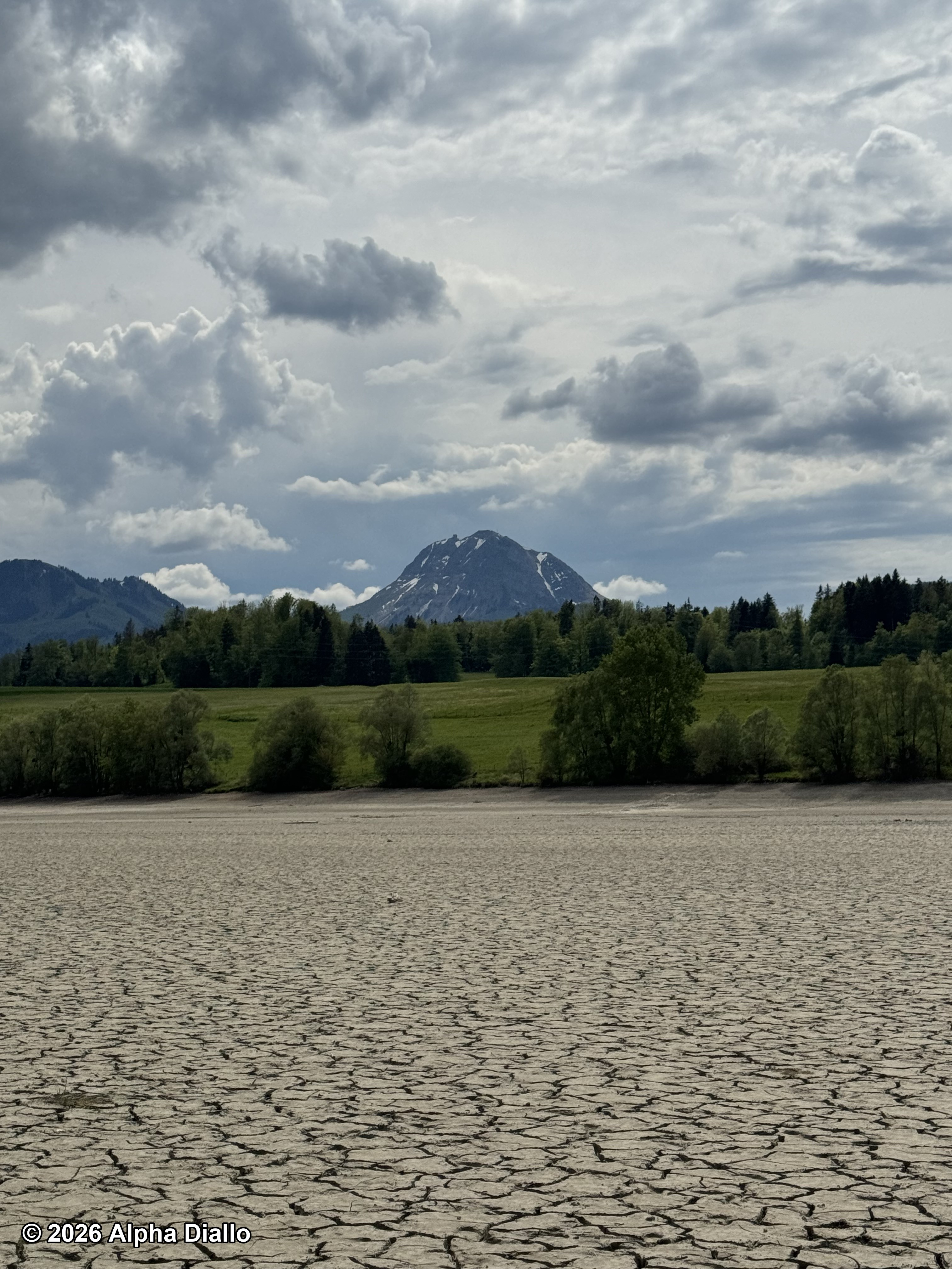 Contraste entre le lit du Lac de la Gruyère asséché, de la verdure et du majestueux Moléson en fond
